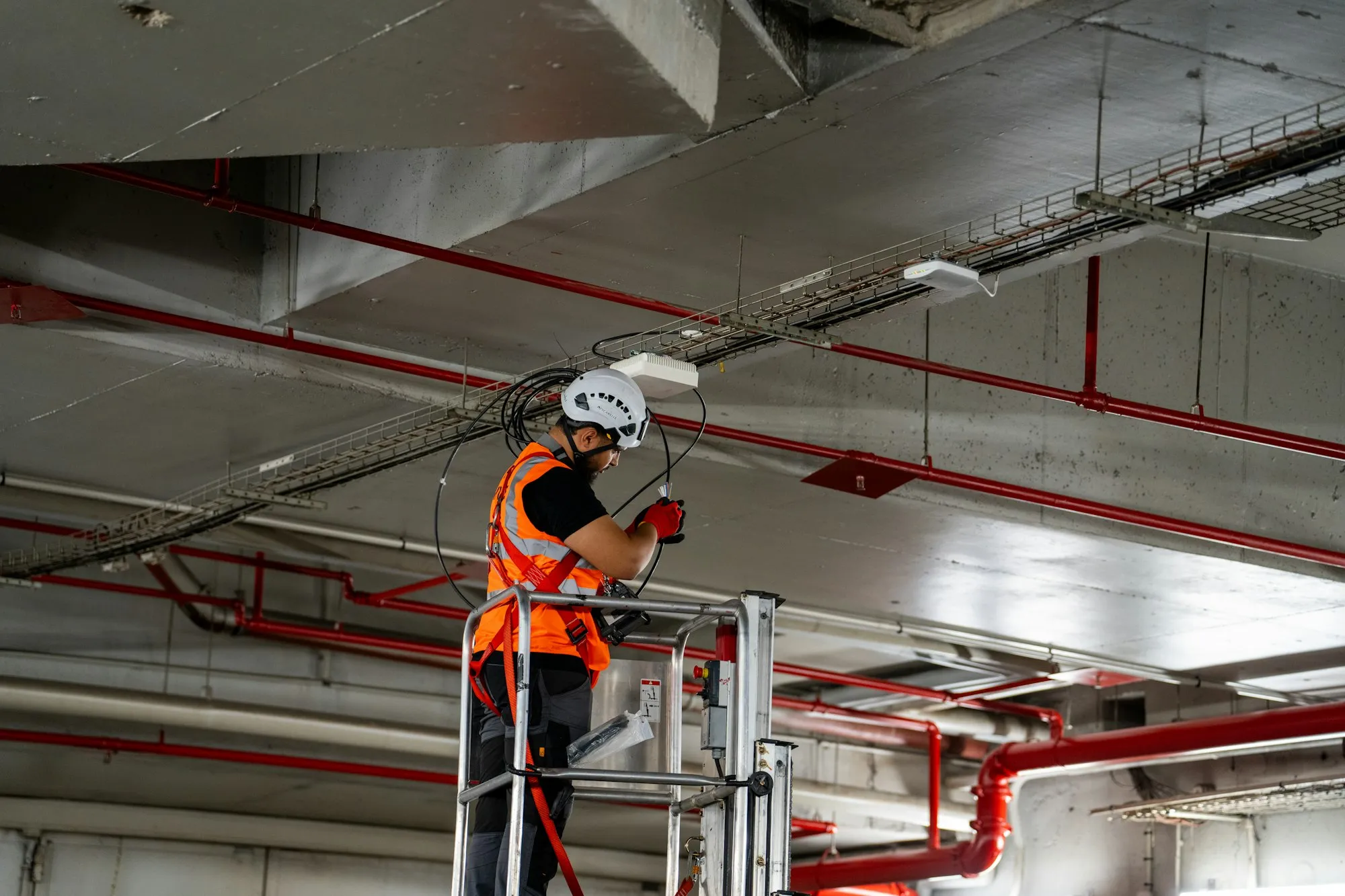 Tradesperson installing ceiling components on a lift