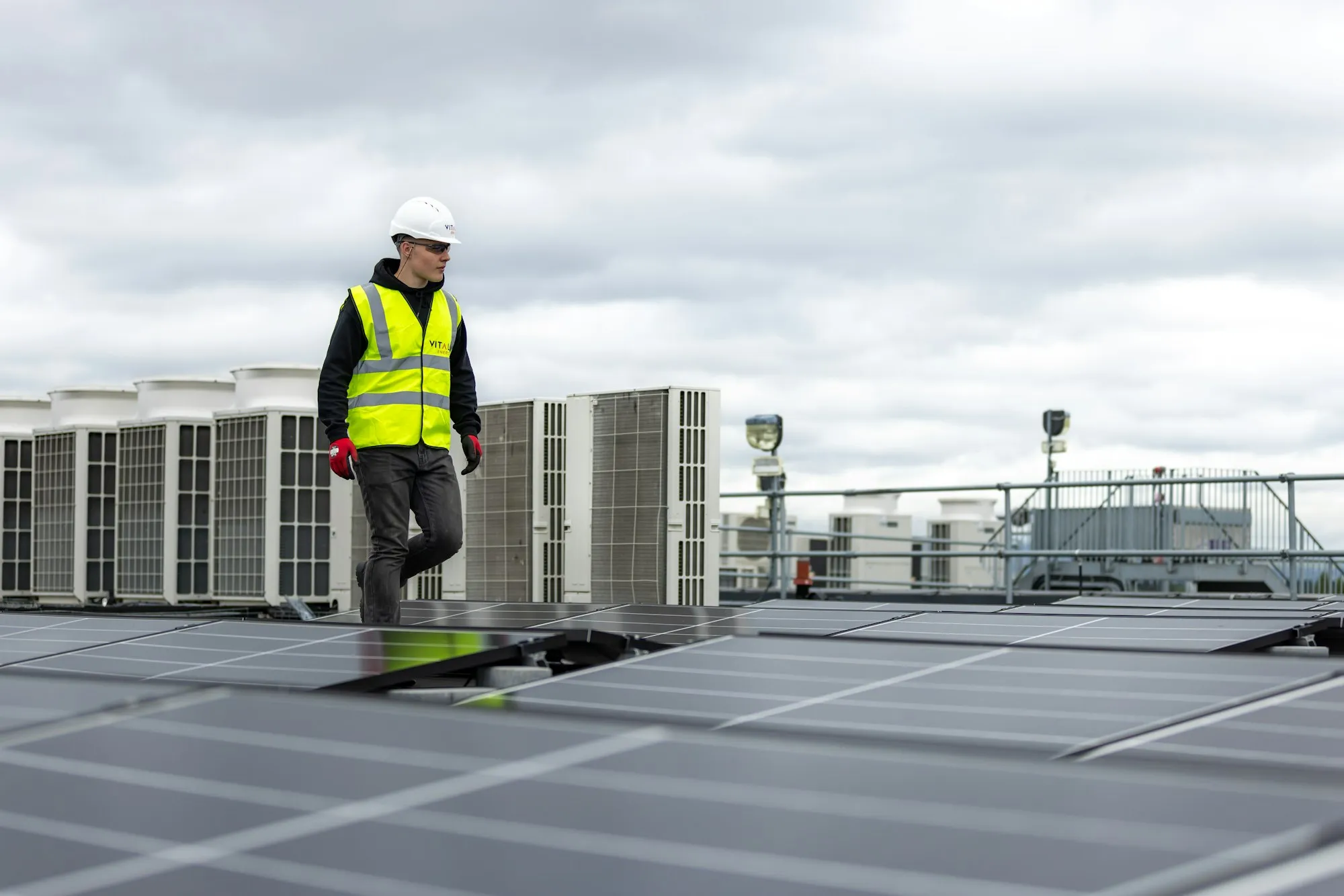 Technician walking across a commercial rooftop between HVAC units