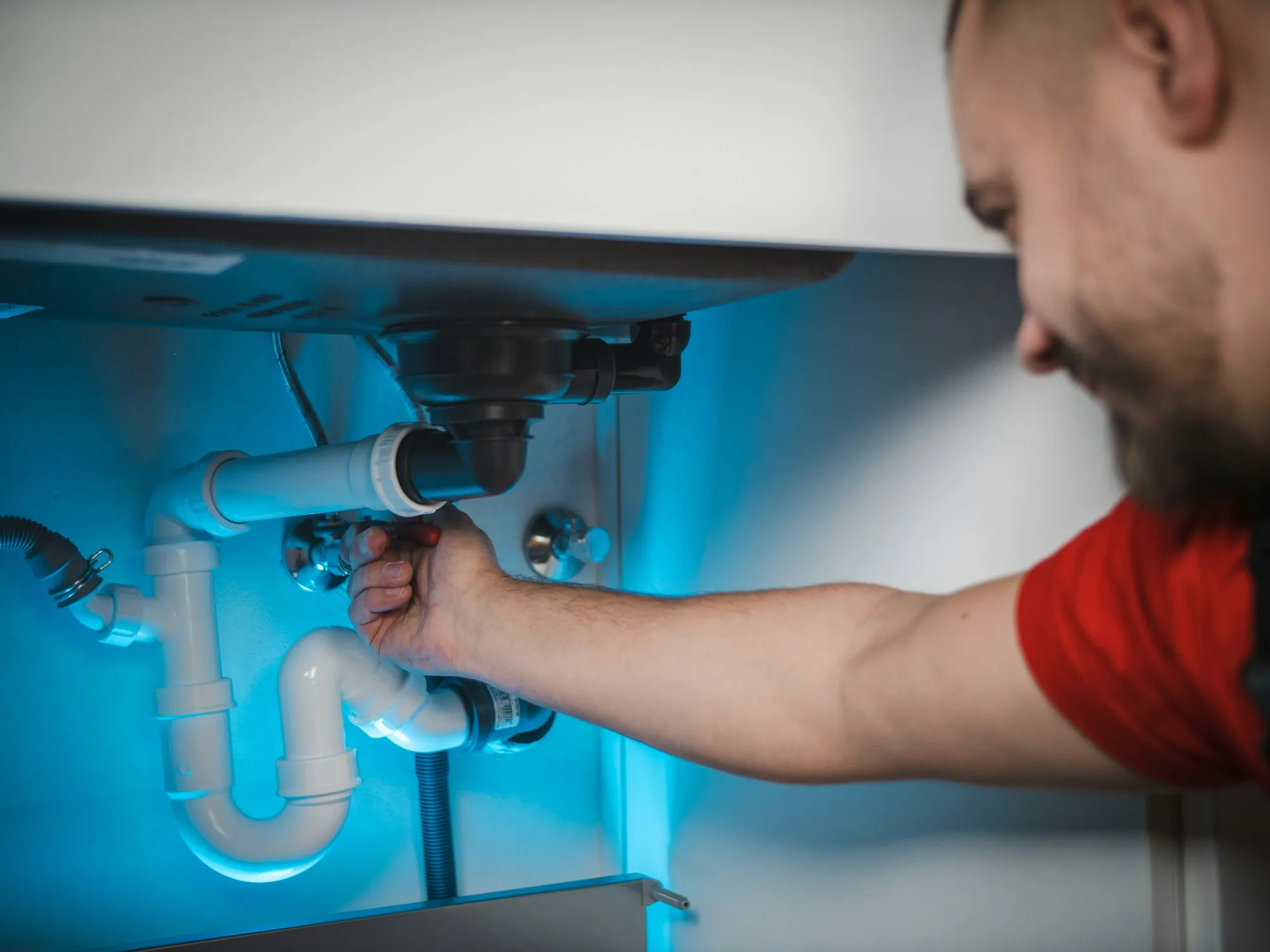 Technician repairing plumbing under a sink